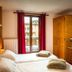 Chalet Hotel Régina room in Les Gets with twin beds, red curtains, wooden wardrobe and window view