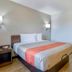 Motel 6 Santa Rosa Nm guest room with queen bed, bedside table, wall lights, and yellow chair in Santa Rosa