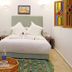 Riad Zanouba in Marrakech guest room with a bed, patterned rug, carved wooden doors, and colorful window