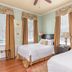 The Beaufort Inn in Beaufort guest room with two beds, wood floors, and tall windows