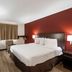 Red Roof Inn Bristol guest room with king bed, red accent wall, desk, TV and window air conditioner