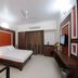 Sai Sangam Hotel in Shirdi guest room with double bed, wall-mounted TV, desk, and curtains