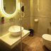 Jullundur Hotel & Restaurant Chandigarh bathroom with lit oval mirror, vessel sink, and toilet