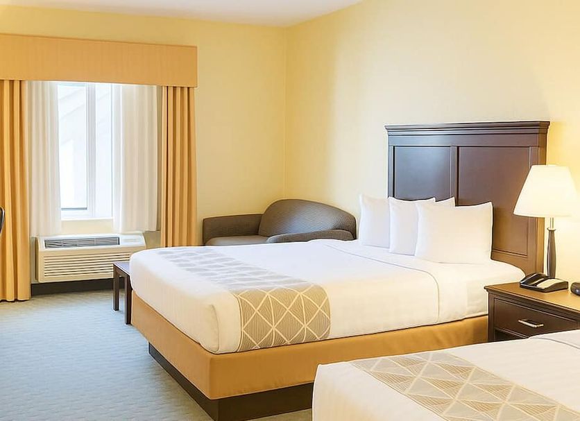 Ambassador Inn and Suites Tuscaloosa guest room with two beds, desk, and window air conditioner