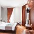 Splanzia Boutique Hotel in Chania guest room with double bed, wood-paneled wall and tall curtains