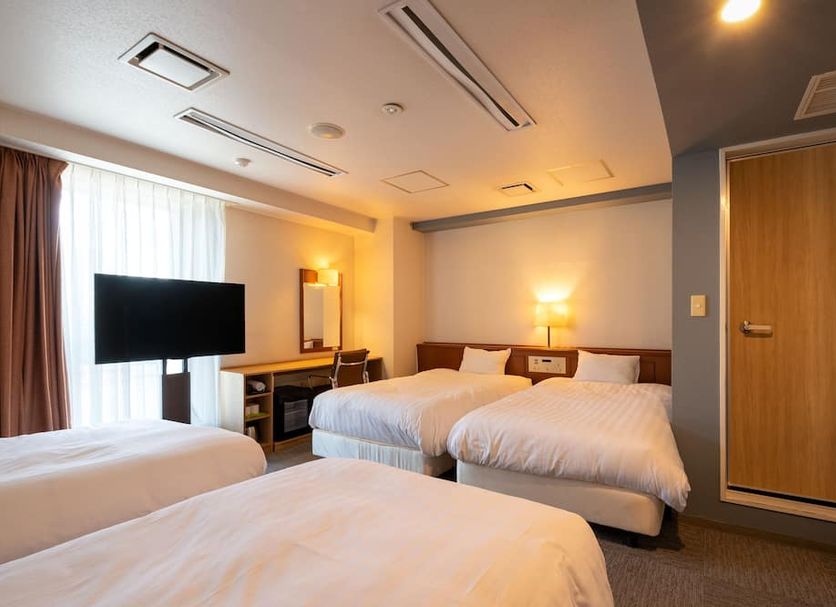 En Hotel Hamamatsu in Hamamatsu guest room with three beds, desk, TV, and warm lighting