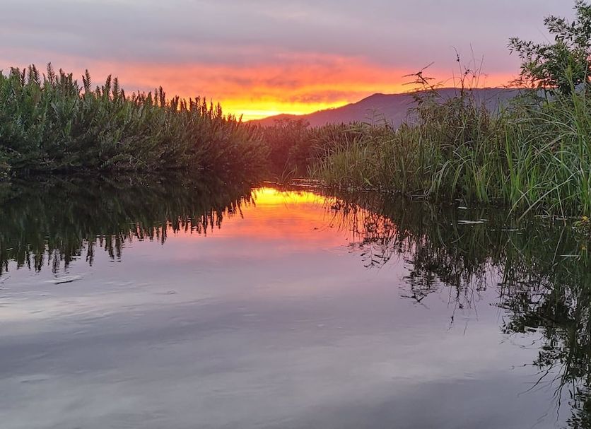 Pousada da Ferrugem in Garopaba with sunset over a reflective lagoon and marsh vegetation