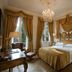 Hotel de la Ville Monza guest room with chandelier, king bed and tall windows in Monza