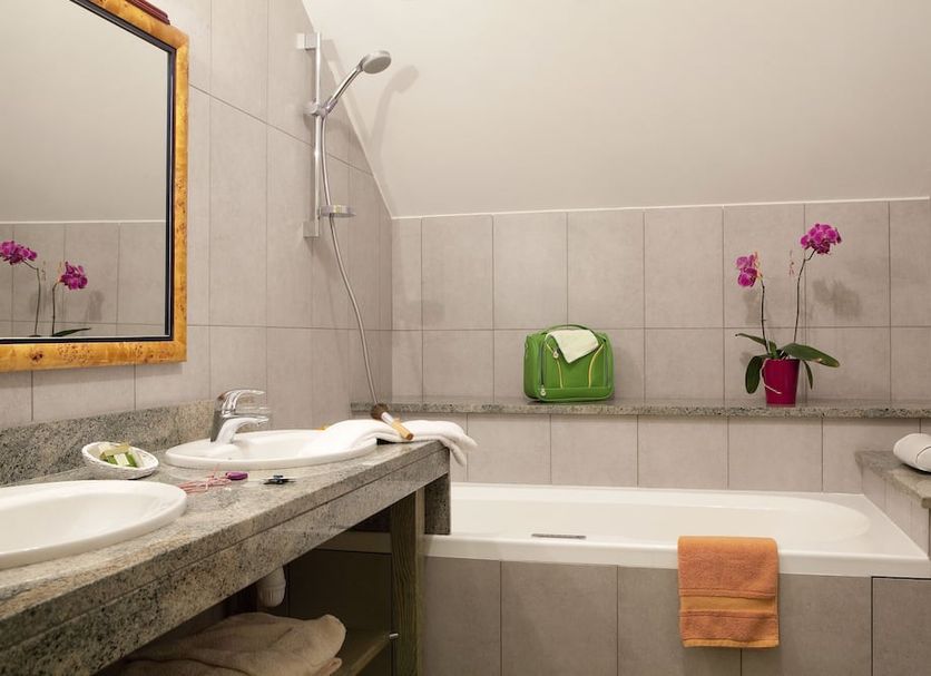 Logis hôtel Ô en Couleur bathroom with bathtub, sink, shower, and orchid in Viévy-le-Rayé