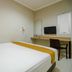The Nagoya Plasa Redpartner room in Batam with a double bed, desk, chair, and wall-mounted TV