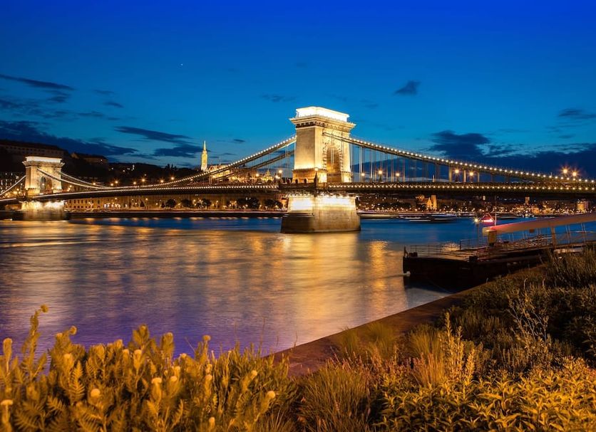Mercure Budapest Korona Hotel in Budapest with illuminated Chain Bridge over the Danube at dusk