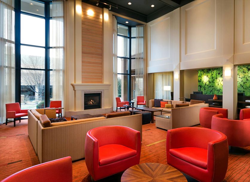 Courtyard by Marriott Kansas City East/Blue Springs lobby with red chairs, fireplace and tall windows in Blue Springs