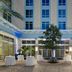 Courtyard by Marriott Delray Beach courtyard with palm trees, round tables, and a central tree in Coral Springs