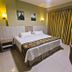 Megal Suites Hotel in Ciudad del Este guest room with king bed, bedside lamps and gold curtains