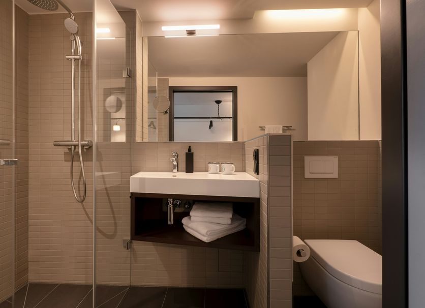 Pierdrei Hotel Hafencity Hamburg bathroom with walk-in shower, sink, toilet and modern lighting