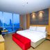 Swiss-Belhotel Mangga Besar in Jakarta guest room with city skyline view and red bench at bed foot