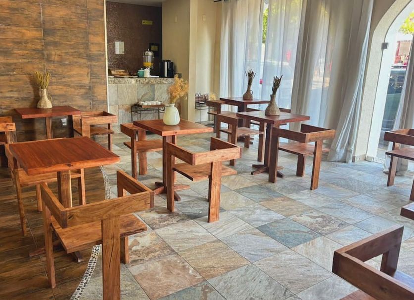 Quinta Nina Playa del Carmen lobby seating area with wooden tables and chairs, sheer curtains, and tiled floor