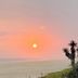 Sunset over the ocean at Hostel Dos Gringos in Maricá, with beach and coastal trees
