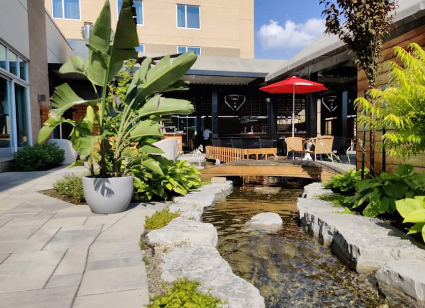 Hotel Mortagne in Boucherville courtyard with tropical plants, pond, patio seating and red umbrella