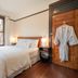 Naramata Inn room with bed, window, bedside lamps and robe hanging on wooden door in Naramata