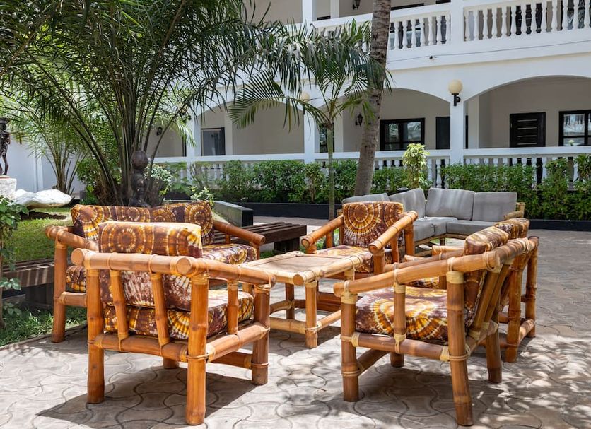 Sarges Hotel in Serrekunda patio seating area with bamboo chairs and tables beside a white building