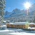 Caravan Park Sexten in Sesto with snow-covered cabins and mountain views under bright sun