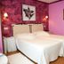 La Solana Montañesa in Comillas: twin beds in a pink guest room with floral wall art and bedside lamps