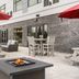 Cambria Hotel Spokane Airport patio with fire pit, red umbrellas, dining tables and lounge seating in Spokane