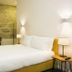 Bo - Álvares Cabral Guesthouse in Porto room with bed, stone wall seating nook, and bedside lamps