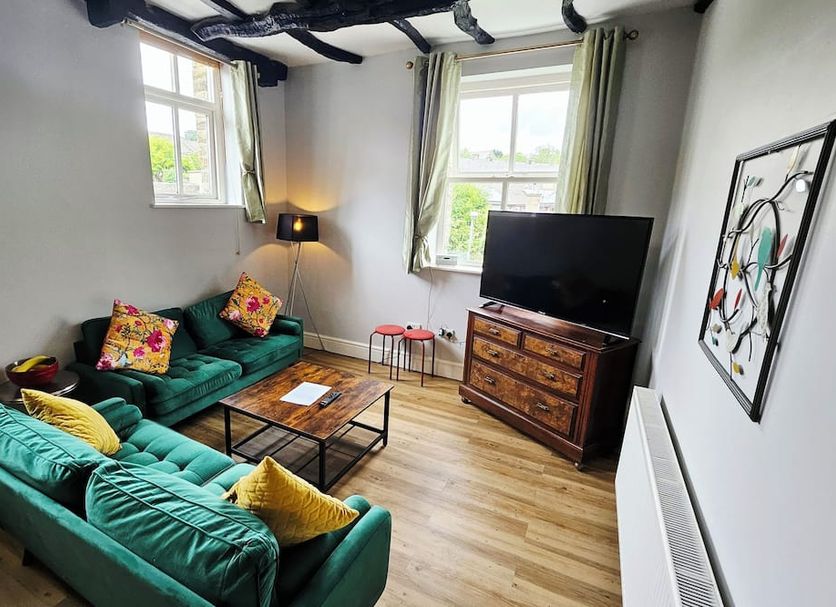 The Lawrence, Burnley: stylish lounge with teal sofas, coffee table, TV and windows