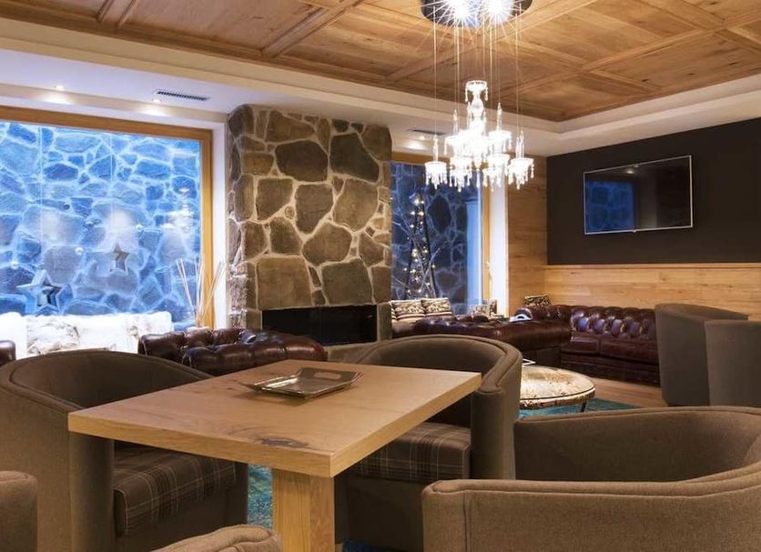 Chalet Marcora in Campitello di Fassa lounge with leather seating, stone fireplace and wood-paneled ceiling