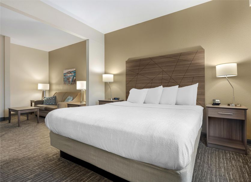 Best Western Brockport Inn & Suites room with king bed, bedside lamps, and mirror in Brockport