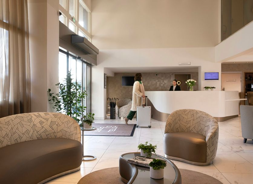 Hotel Du Port in Nogent-sur-Marne lobby with curved front desk, seating area, and tall windows