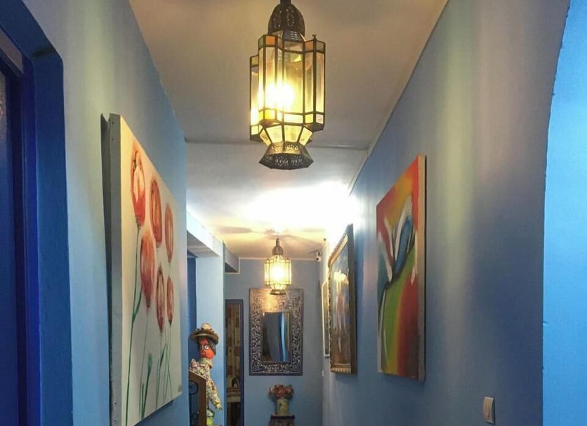 Dar Bouanani Asilah hallway with blue walls, checkered tile floor and hanging lanterns