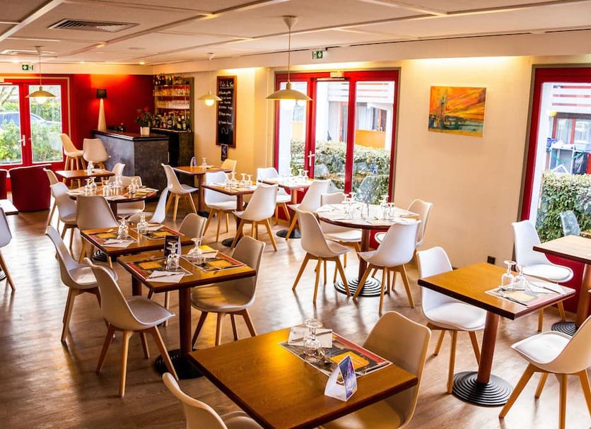initial by balladins La Roche-sur-Yon dining room with modern tables, chairs and red-framed windows