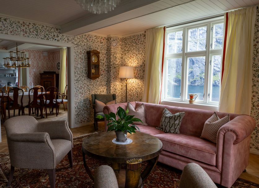 Nusfjord Village & Resort in Ramberg: cozy lounge with pink sofa, round table, armchair and large window