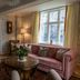 Nusfjord Village & Resort in Ramberg: cozy lounge with pink sofa, round table, armchair and large window