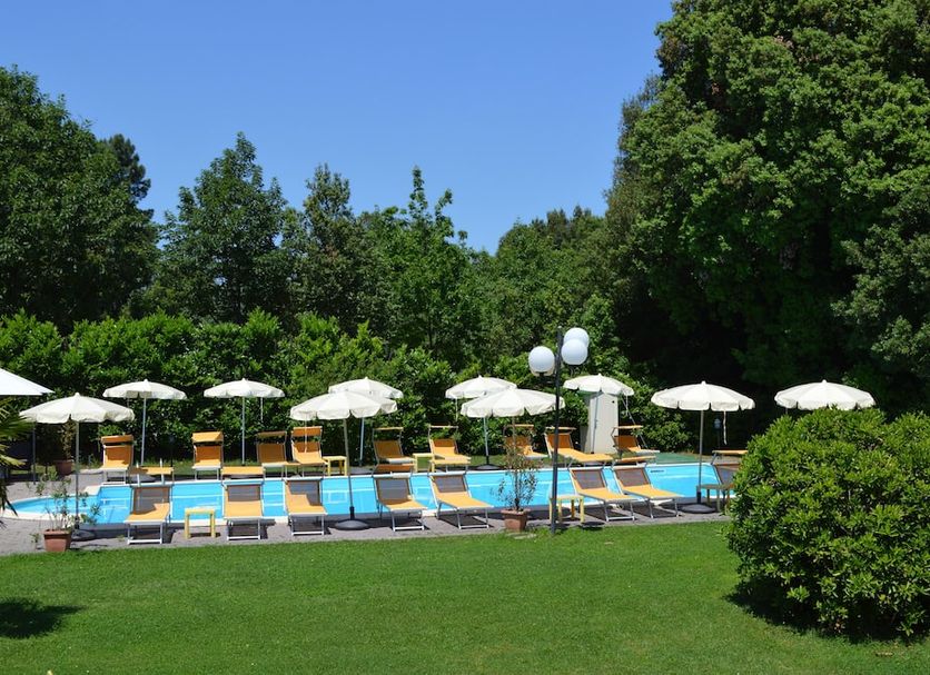 Hotel Monti in Lamporecchio: outdoor pool with lounge chairs, white umbrellas, and garden lawn