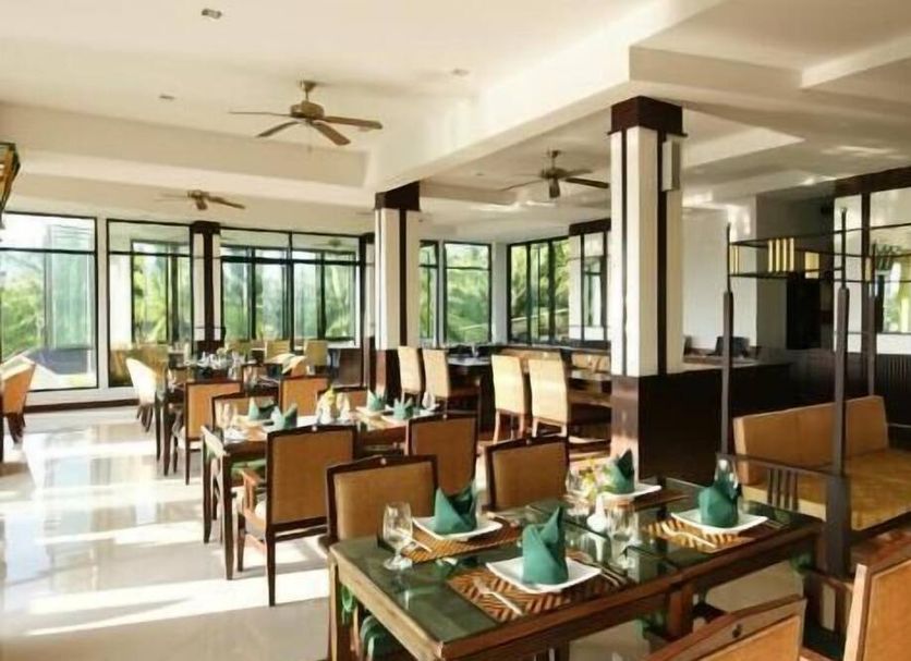 Palm Paradise, Aonang Resort in Krabi dining room with large windows, ceiling fans, and set tables