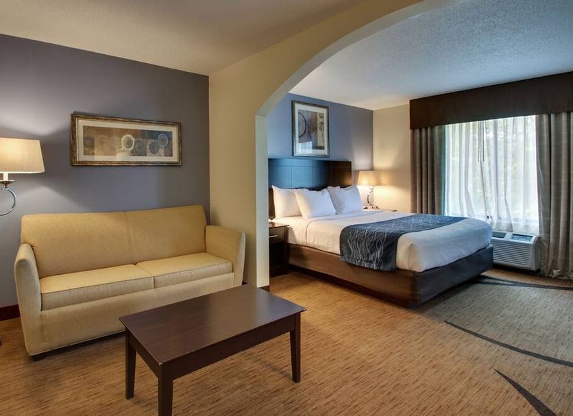 Wingfield Inn & Suites in Owensboro guest suite with sofa, coffee table, and king bed by window