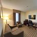 Sonesta Essential Hotels Overland Park room with sofa, desk, TV, and sitting chair
