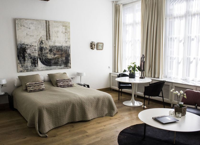 Galerie Hotel Dis Maastricht guest room with double bed, large windows, round tables and artwork