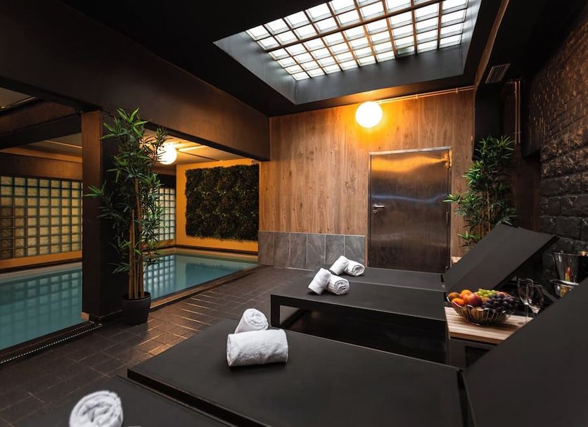 Hotel Orion in Ghent spa room with indoor pool, wooden lounge beds, and skylight