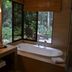 Hotel Jungle Lodge Tikal bathroom with soaking tub and rainforest-view windows in Tikal