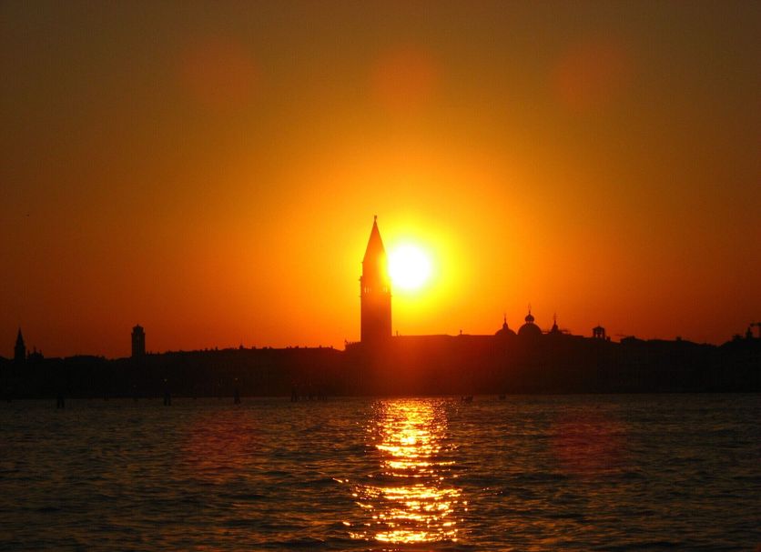 Sunset over Venice lagoon with St. Mark's bell tower silhouetted above water at Oasis Lagoon Estate