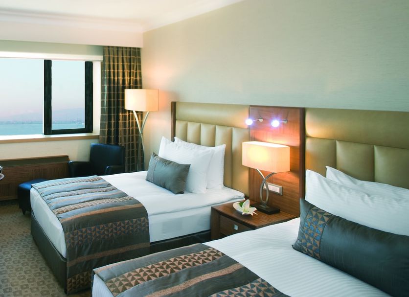 Mövenpick Hotel Izmir guest room with twin beds, desk, and sea view