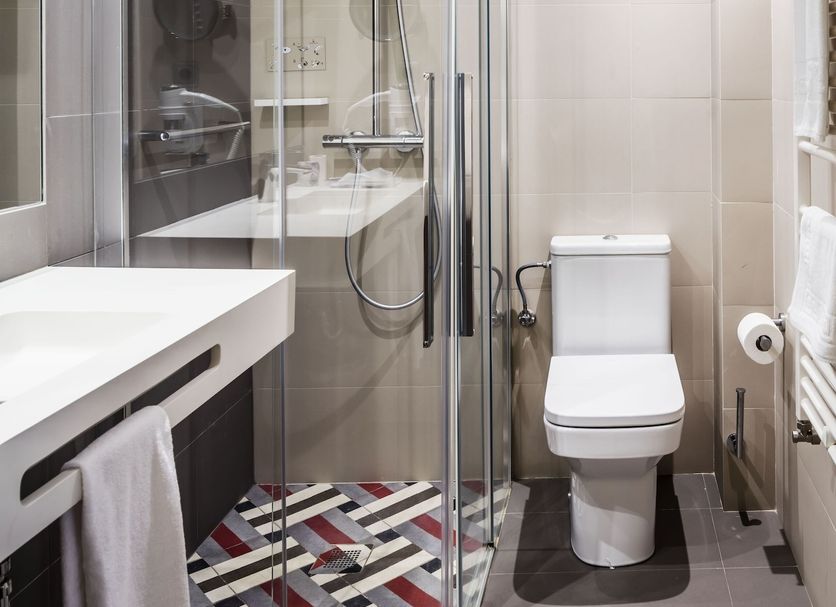 Balneari Termes Victòria bathroom with glass shower, toilet and geometric tiled floor in Caldes de Montbui