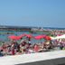 Hotel Rosa Del Tirreno in Quercianella with crowded beach loungers and umbrellas beside the sea