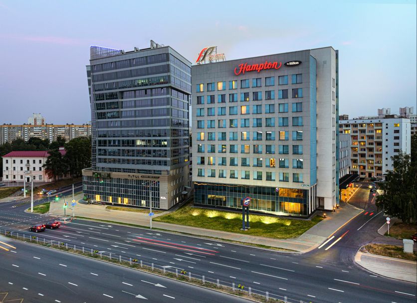 Hampton by Hilton Minsk City Centre hotel exterior in Minsk beside a modern glass tower at dusk
