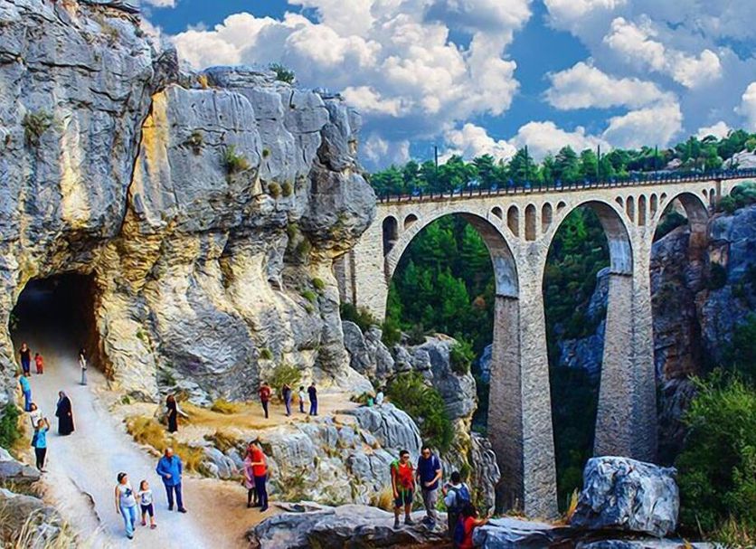 Adana Saray Hotel in Adana with cliffside walkway and stone viaduct over a green gorge